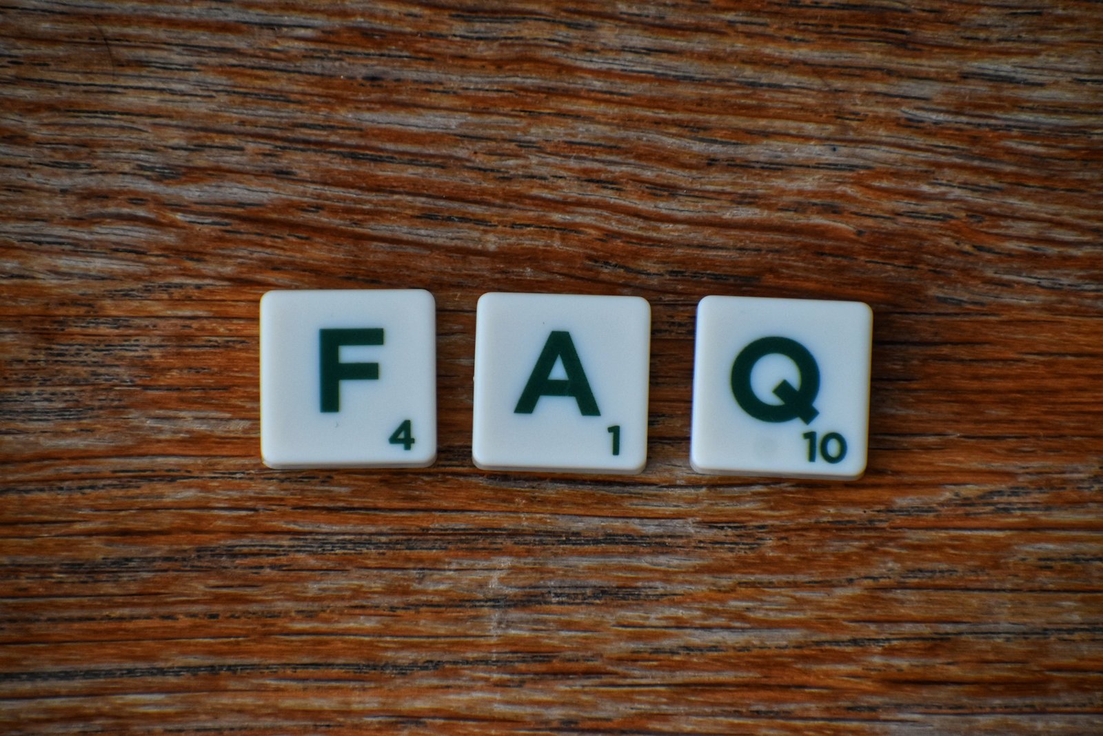 FAQ blocks arranged on wooden tiles representing frequently asked questions about conscious living, freedom lifestyle, online business and personal growth.